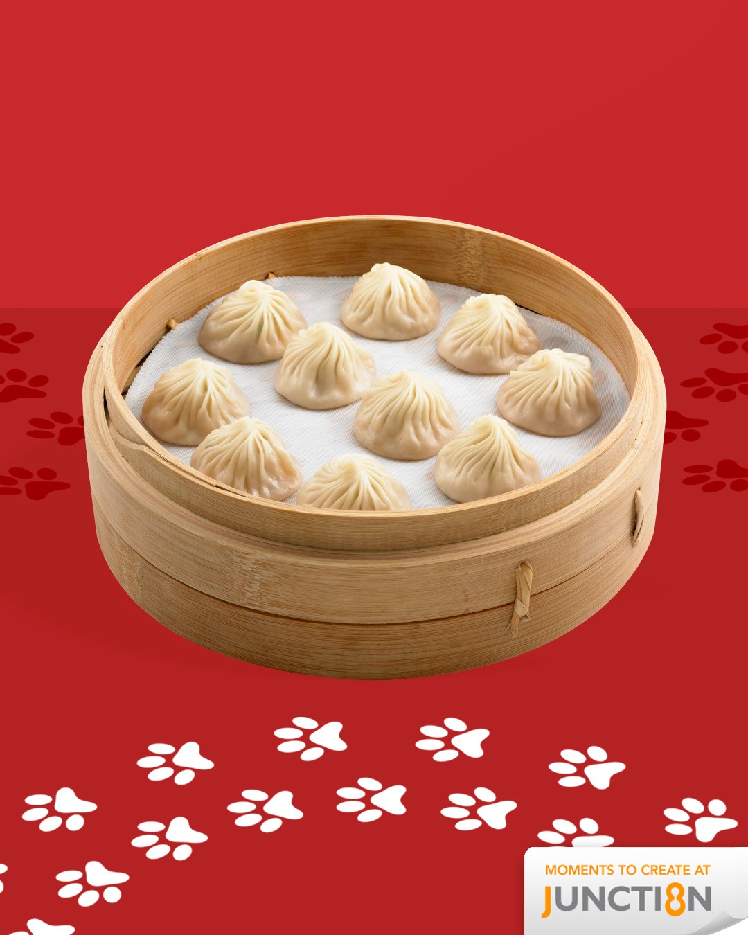 A basket of freshly steamed pork xiao long baos, some with a spoon revealing the savory broth inside.