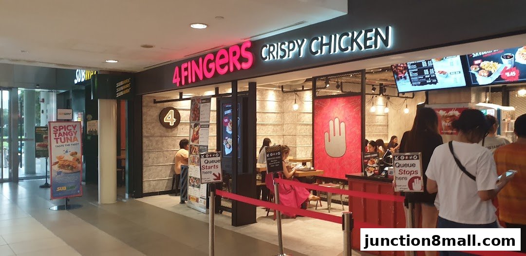 The exterior of a 4 Fingers Crispy Chicken restaurant with a queue forming.
