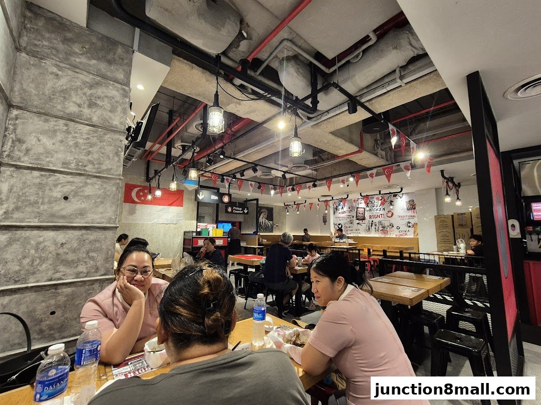 Diners enjoy crispy chicken at 4 Fingers restaurant with Singaporean flags and festive decorations.