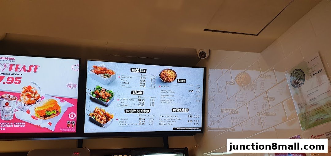 A digital menu board displaying various crispy chicken combos, rice boxes, salads, seafood, sides, and beverages.