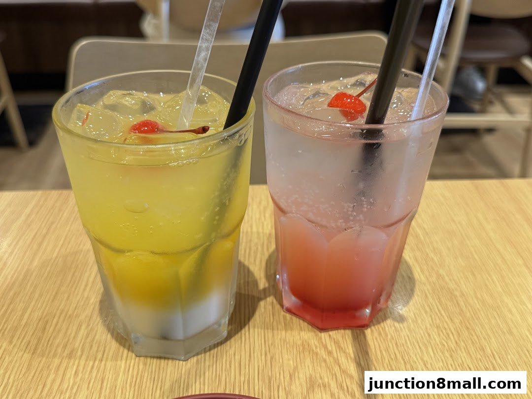 Two refreshing drinks, one yellow and one pink, garnished with cherries and straws.