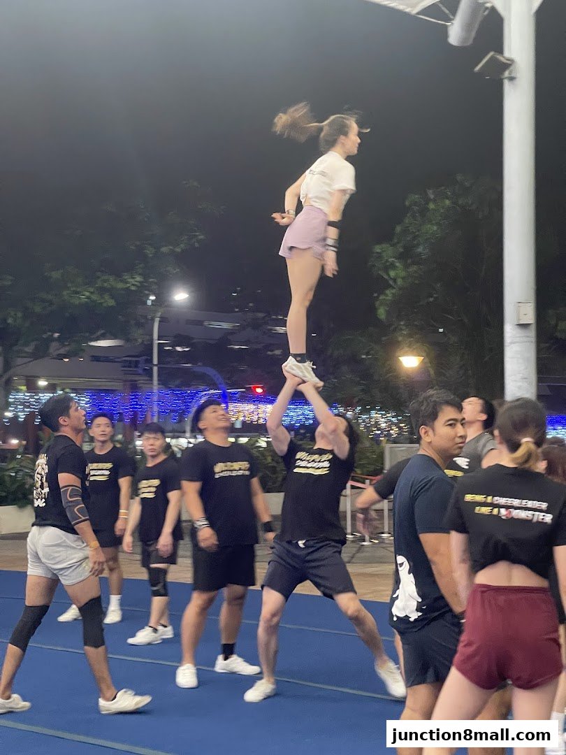 A cheerleading team practices a stunt with a flyer being lifted by teammates.