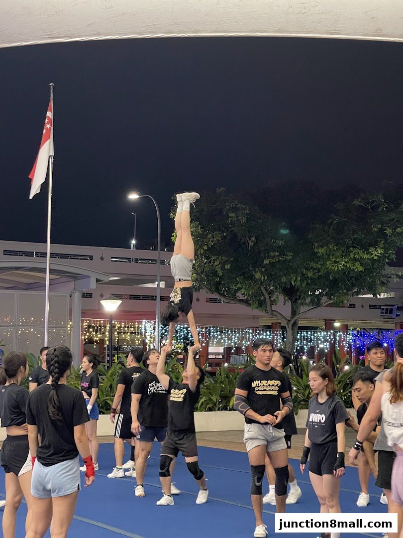 A group of people practicing cheerleading stunts outdoors at night.
