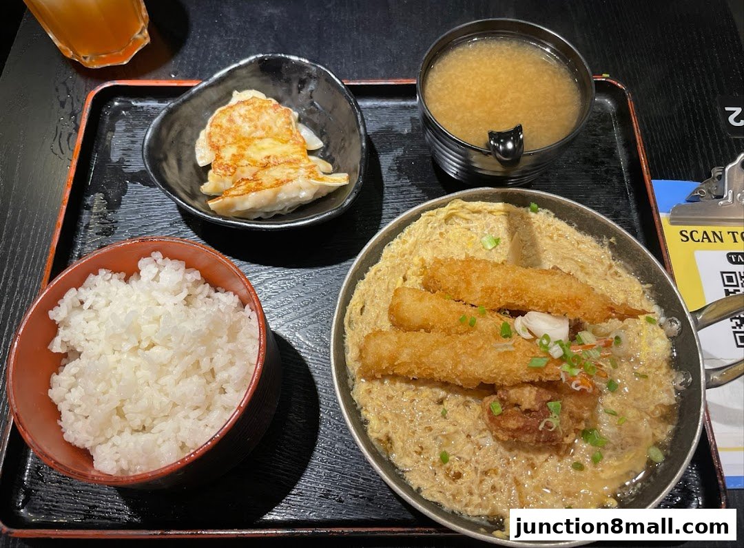 A delicious Japanese meal featuring rice, miso soup, gyoza, and a main dish with fried shrimp and chicken.