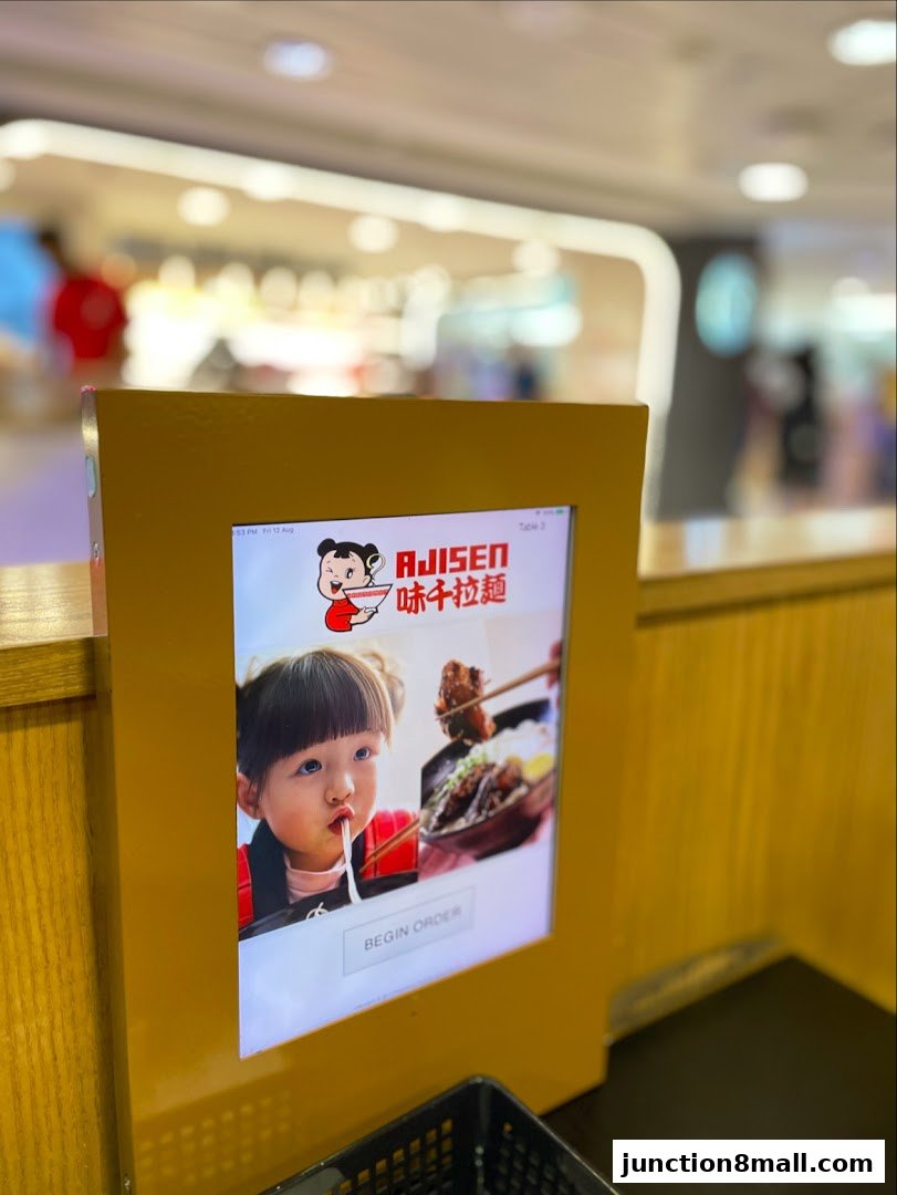 A digital ordering kiosk at Ajisen Ramen featuring a child eating noodles.