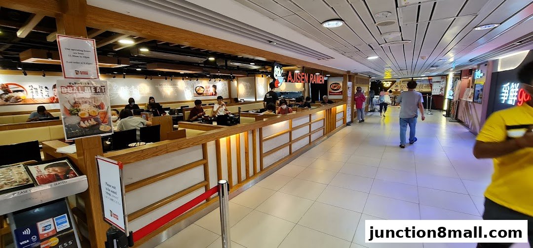 Interior view of Ajisen Ramen restaurant with customers dining and a promotional poster.