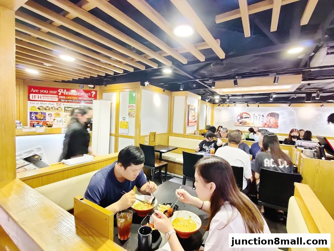 Diners enjoy ramen at Ajisen Ramen, with a membership promotion visible at the counter.