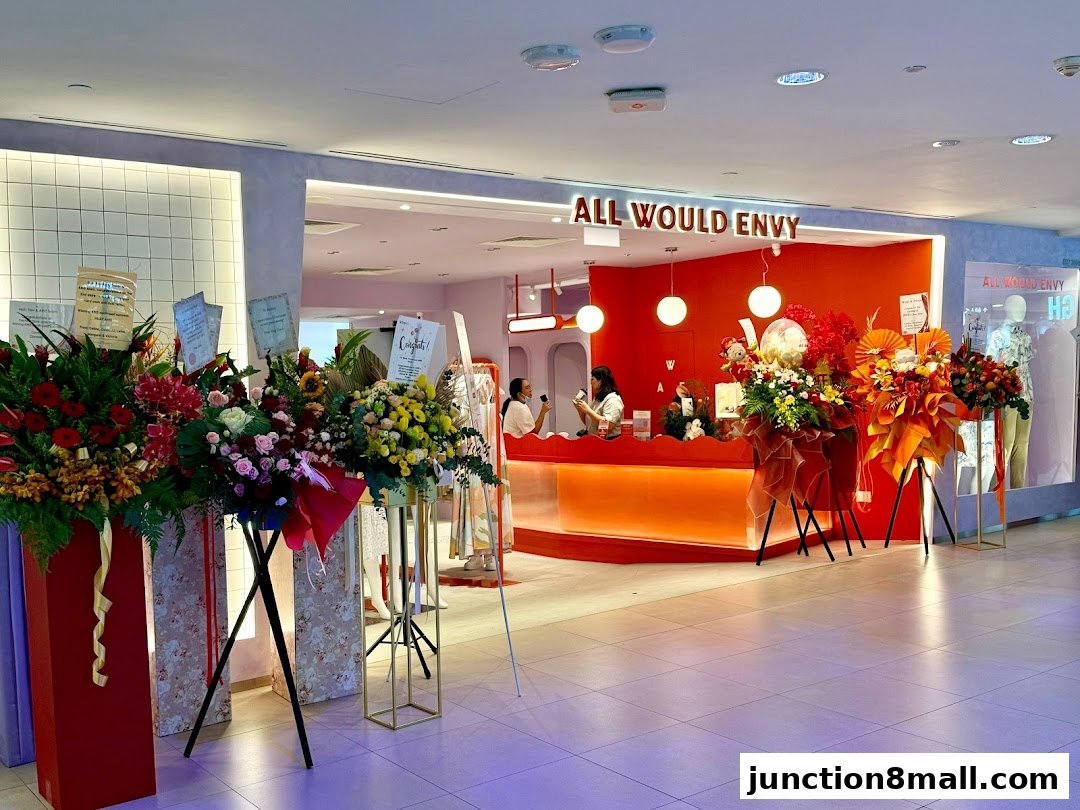 The entrance of ALL WOULD ENVY shop with floral decorations and staff at the counter.