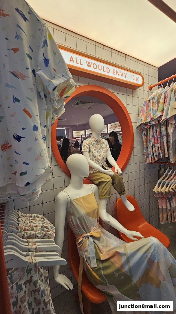 Mannequins display colorful clothing inside a brightly lit boutique with a prominent store sign.