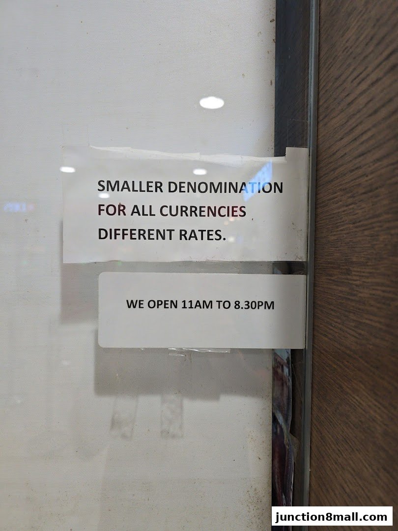 Signage on a shop window indicating currency exchange services and operating hours.