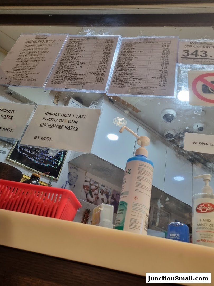 Exchange rates displayed on boards inside a money exchange shop, with hand sanitizer visible.
