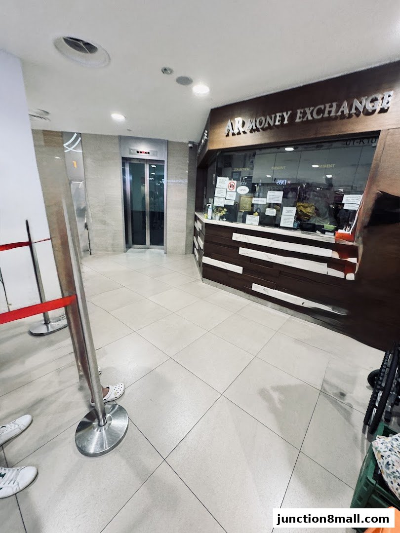 The AR Money Exchange shop front with an elevator and queue barriers in the foreground.