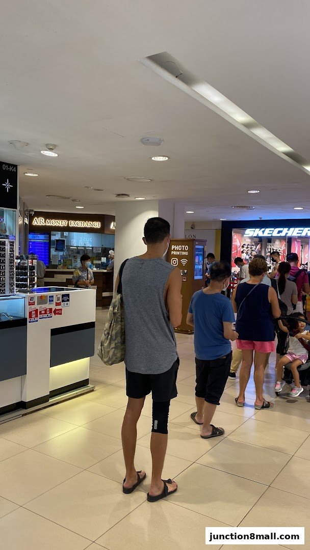 People queuing at AR Money Exchange and other shops in a mall.