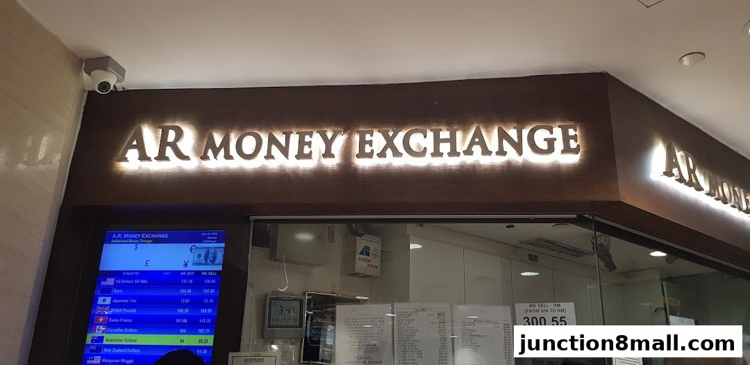 The illuminated sign of AR Money Exchange with currency exchange rates displayed on a screen.