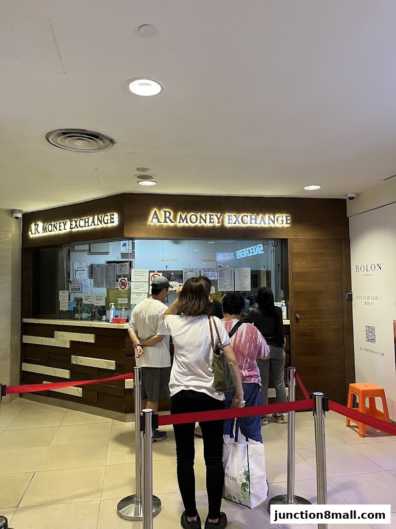 People queue at AR Money Exchange, a currency exchange service with a prominent sign.
