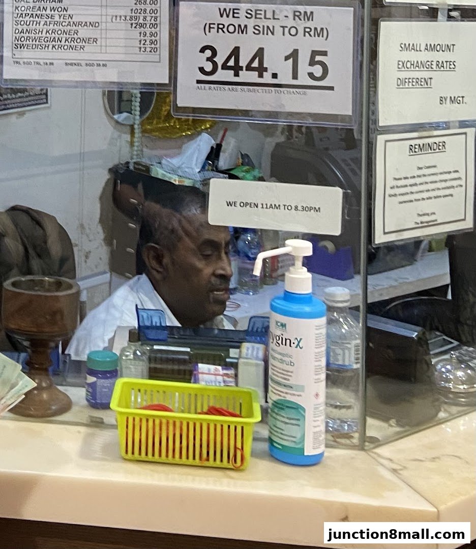 A currency exchange counter with exchange rates displayed and a staff member behind the counter.