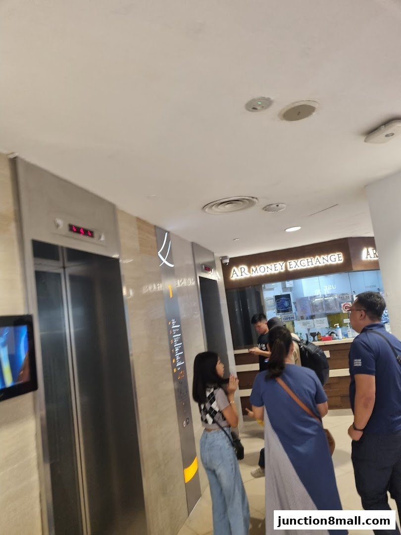 People waiting near elevators and the AR Money Exchange shop counter.
