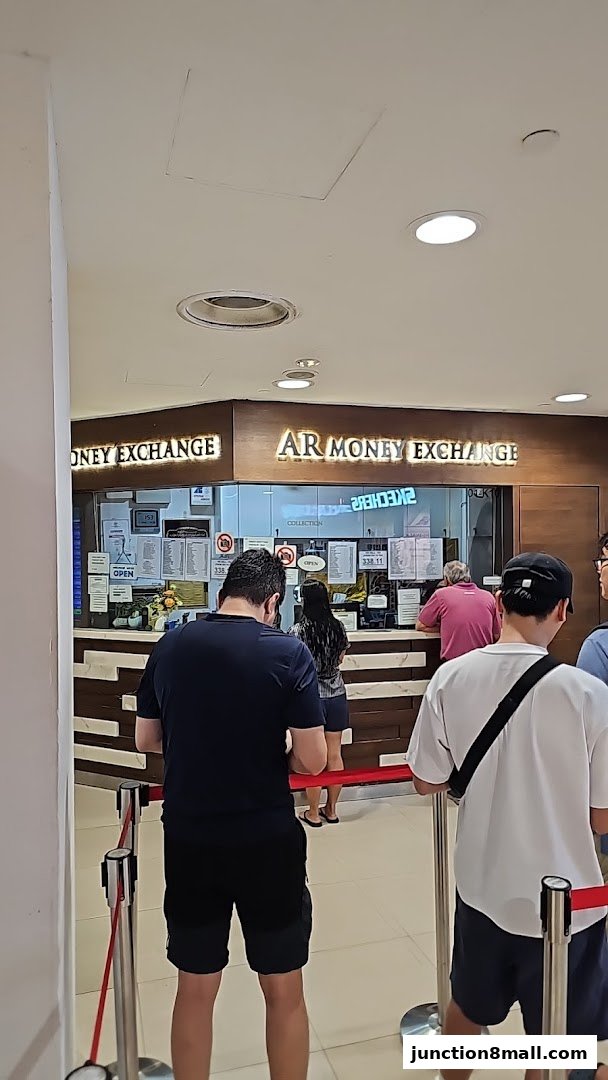 People queue at AR Money Exchange counter for currency exchange services.