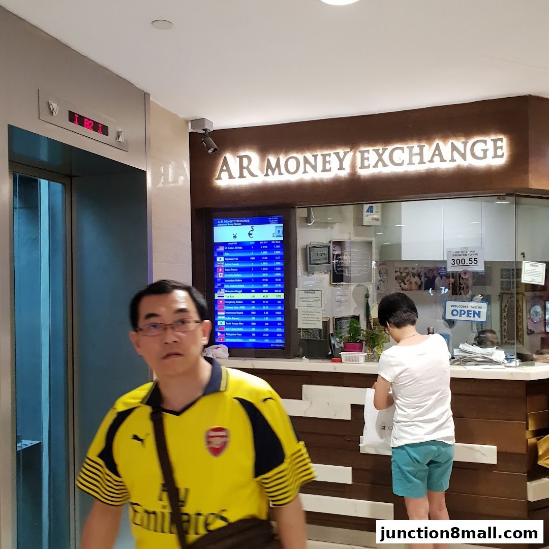 AR Money Exchange shop with a digital display of currency rates and staff serving customers.