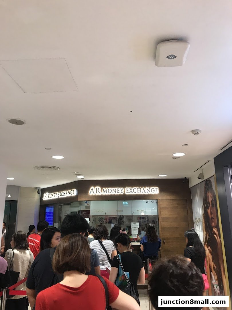 People queuing at the AR Money Exchange counter inside a shopping mall.
