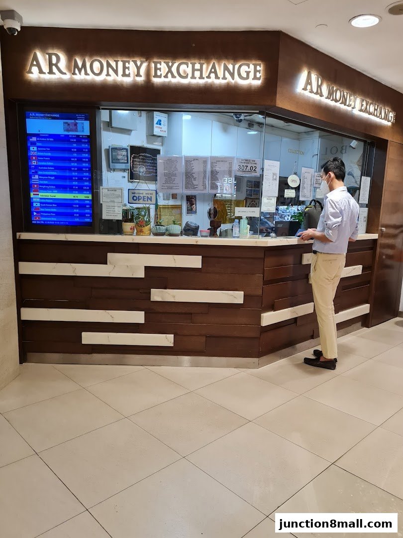 AR Money Exchange shop front with a digital display showing currency rates and a customer at the counter.