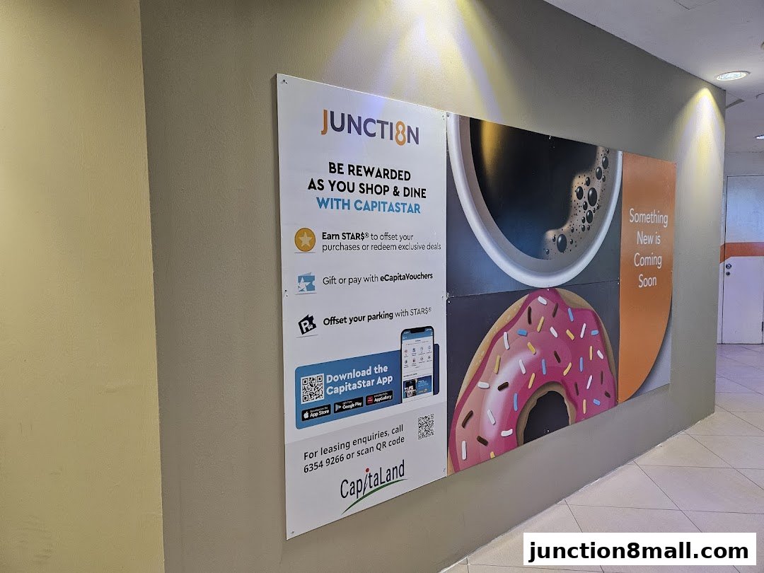 A wall advertisement for Junction 8 mall, promoting the CapitaStar rewards program with images of coffee and a donut.