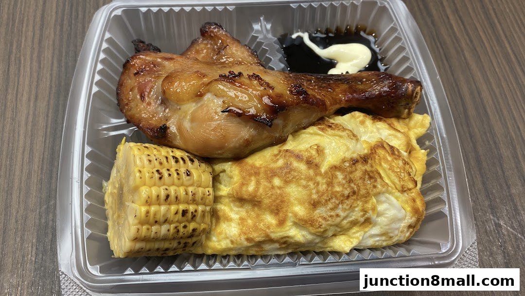 A takeout container filled with grilled chicken, corn on the cob, and an omelet.