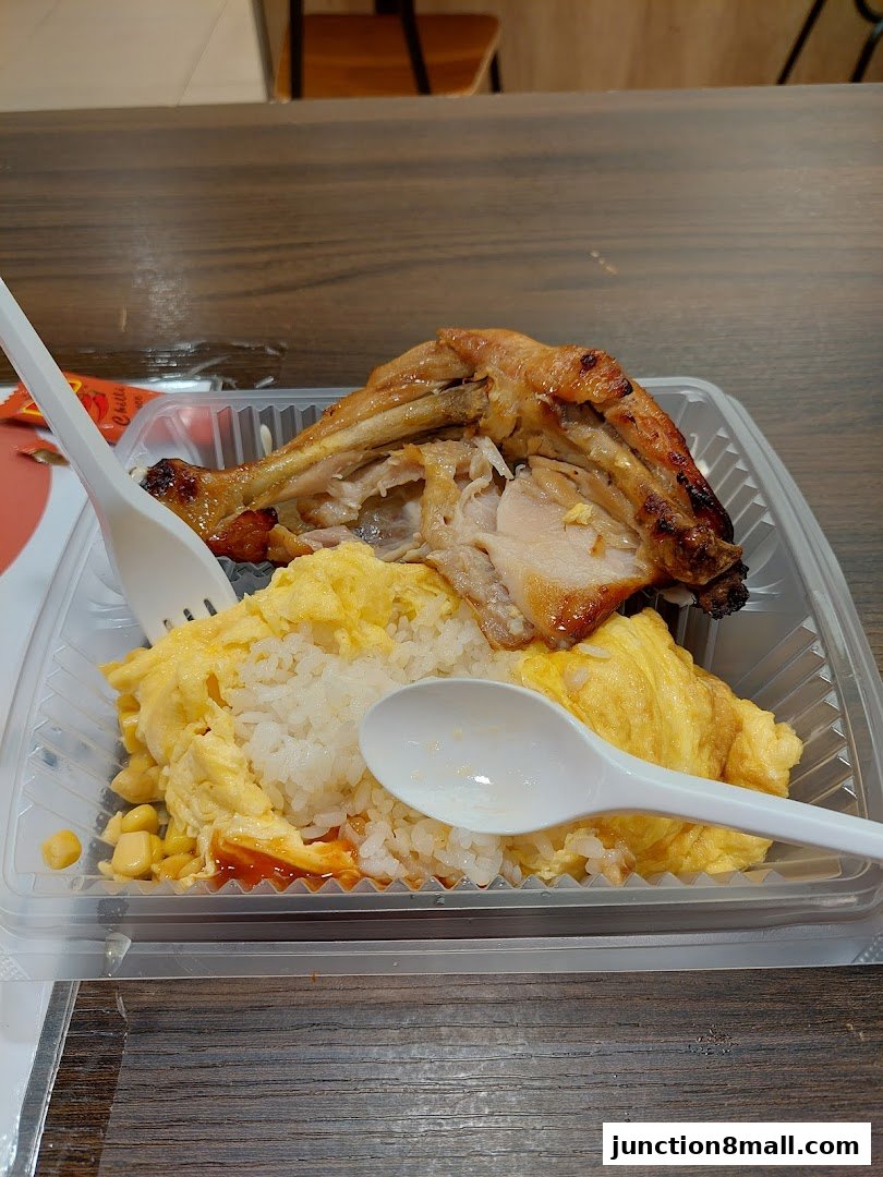 A takeout container filled with rice, scrambled eggs, and a piece of grilled chicken.