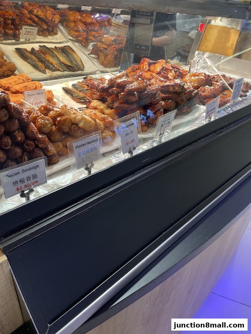 A display case filled with various grilled meats, including chicken wings, meatballs, and fish.