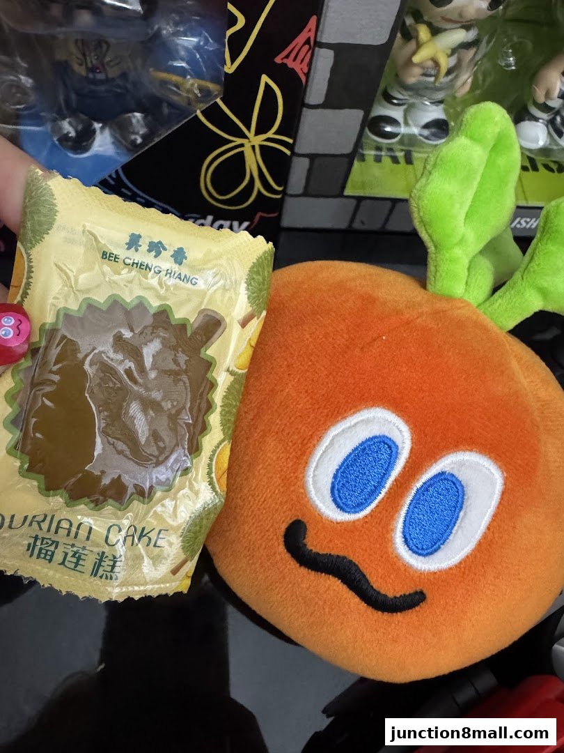 A package of Bee Cheng Hiang Durian Cake next to a plush orange character.