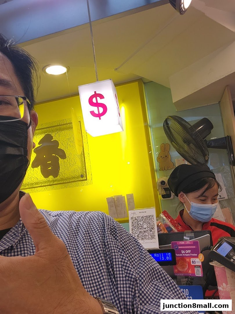 A customer gives a thumbs up at the counter of Bee Cheng Hiang, with a staff member serving.