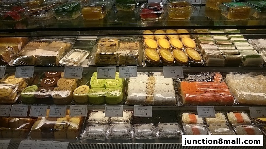 A display case filled with various cakes, pastries, and desserts, neatly packaged and labeled.