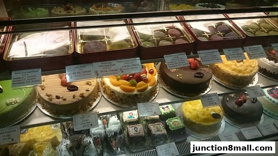 A display case filled with various cakes and pastries, with price labels visible.