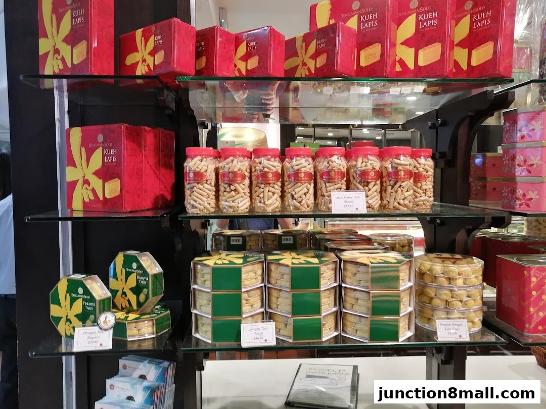 Shelves filled with assorted traditional Indonesian kueh lapis and pineapple tarts in decorative packaging.