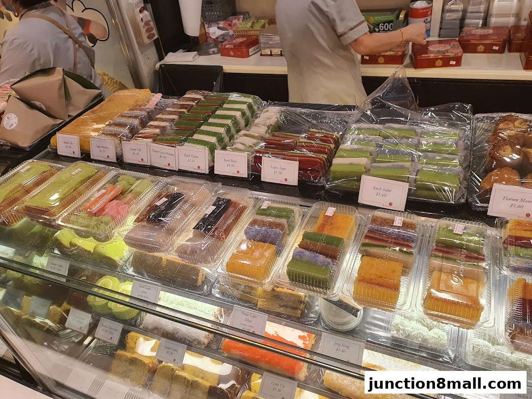 A display of colorful, layered cakes and pastries in clear plastic packaging.