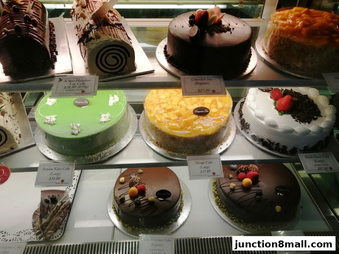 A display case filled with various cakes, including chocolate, fruit, and log cakes.