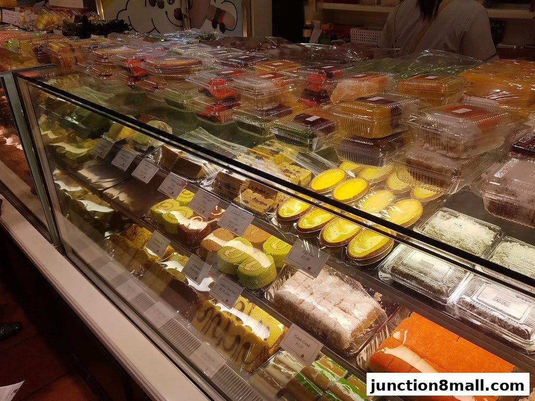 A display case filled with various cakes, pastries, and desserts, neatly packaged.