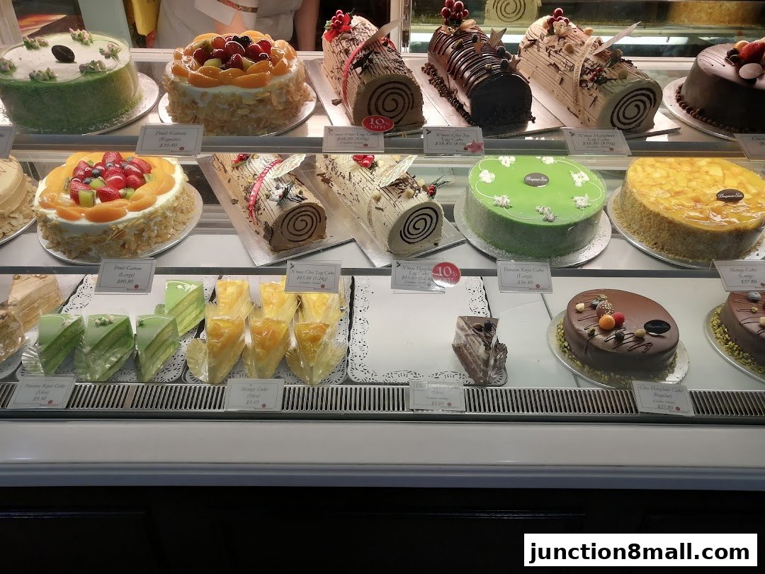 A display case filled with various cakes, including log cakes, round cakes, and sliced cakes.