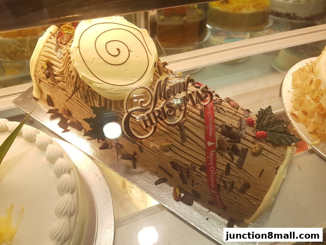 A festive chocolate log cake decorated with 'Merry Christmas' and festive accents.
