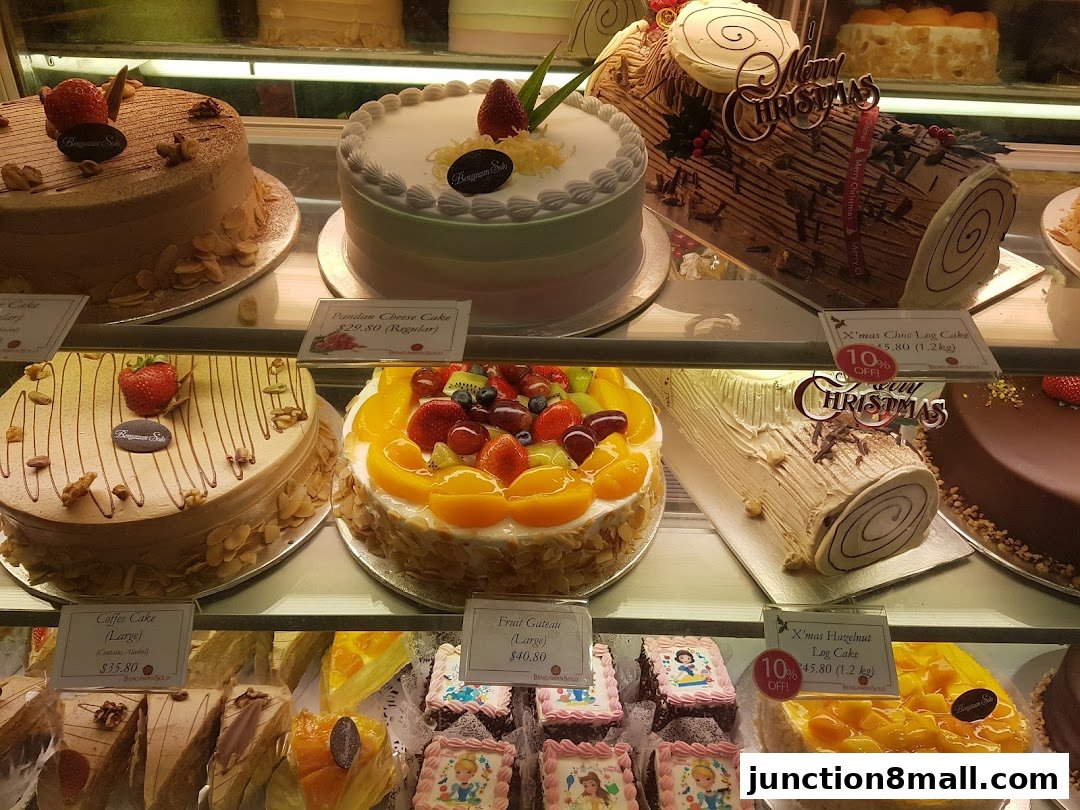 A display of various cakes and log cakes, some with festive Christmas decorations.