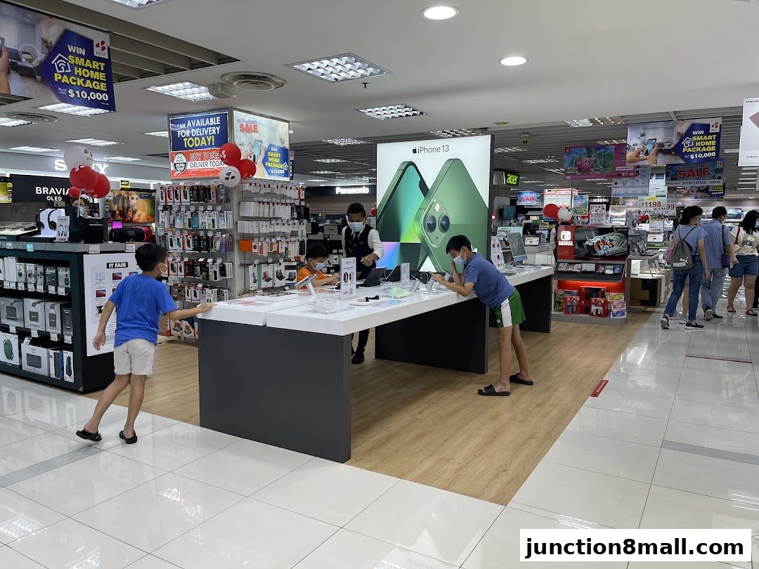Customers browse electronics, including iPhones, in a well-lit retail store.