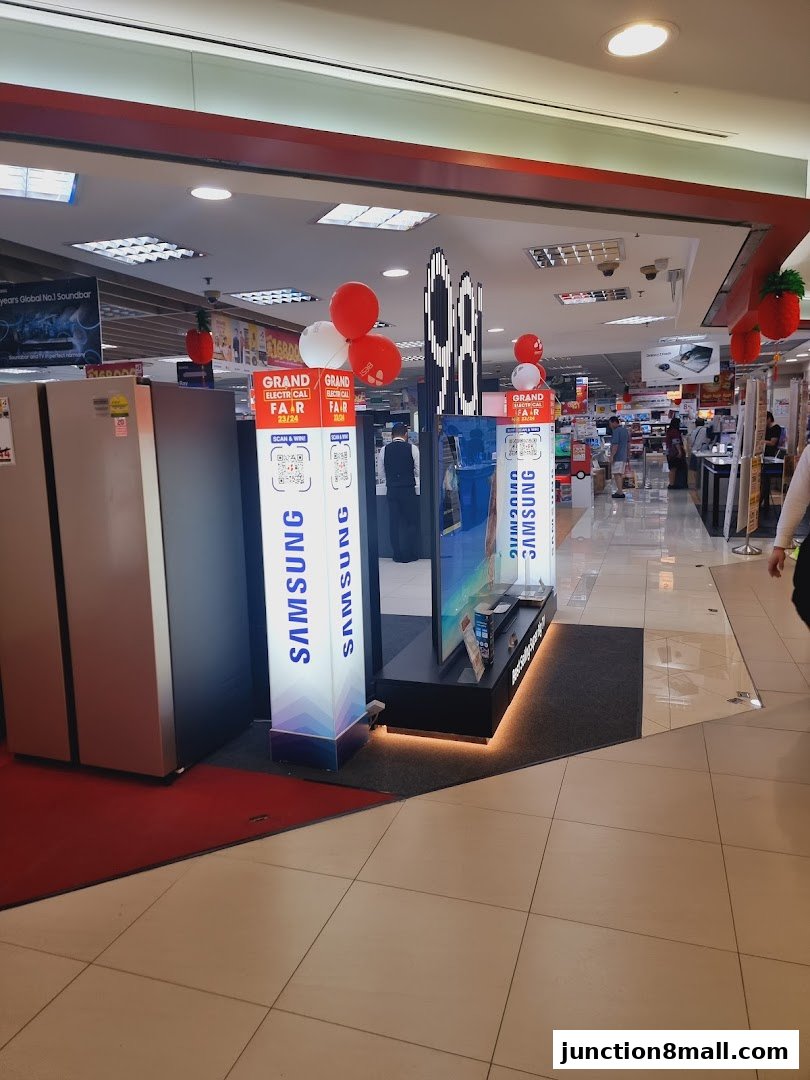 Interior view of an electronics store with refrigerators, TVs, and promotional displays.