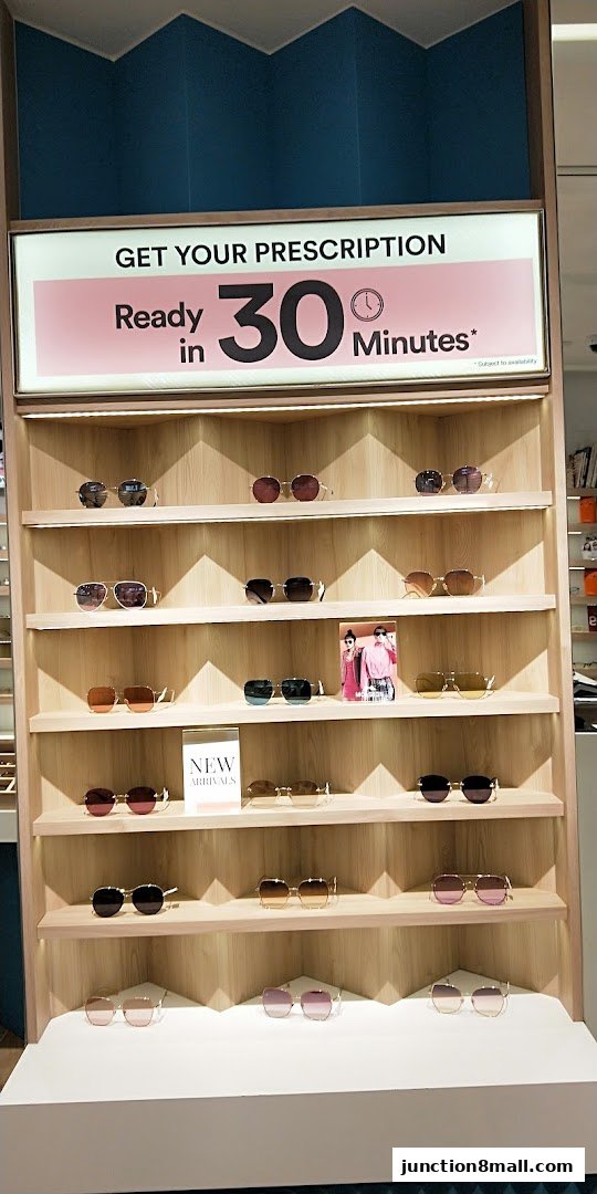 A display of various sunglasses on shelves with a sign advertising prescription eyewear ready in 30 minutes.