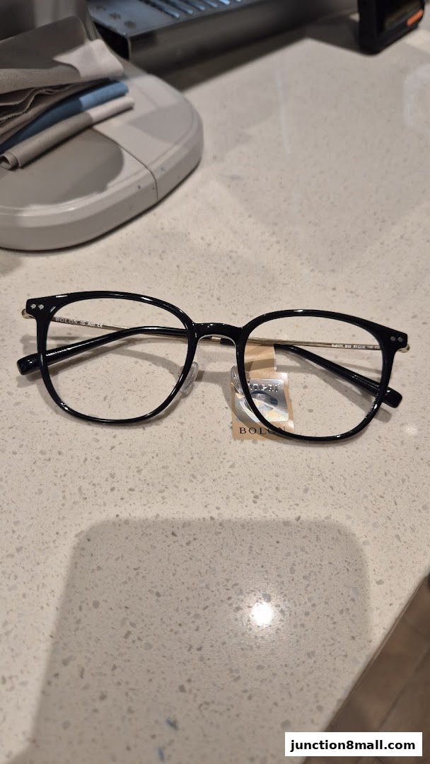 A pair of black Bolon Eyewear glasses with a tag on a speckled countertop.