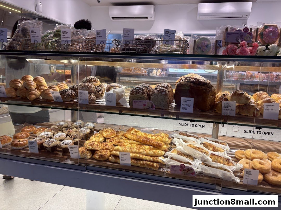 A display case filled with a variety of freshly baked breads, pastries, and donuts.