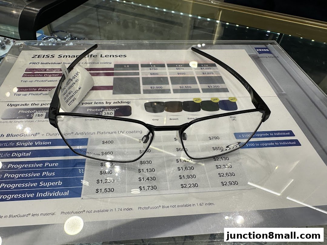 A pair of black eyeglasses displayed on a price list for ZEISS SmartLife Lenses.