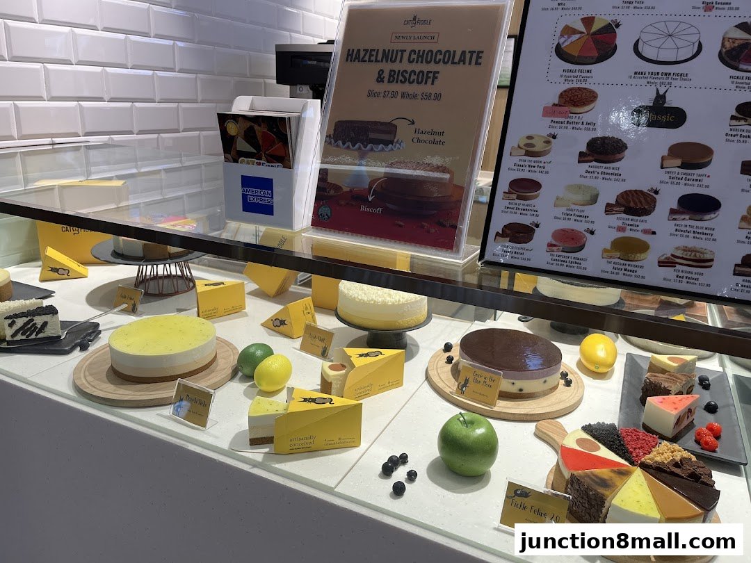 A display case filled with various cakes and desserts, with a menu board in the background.