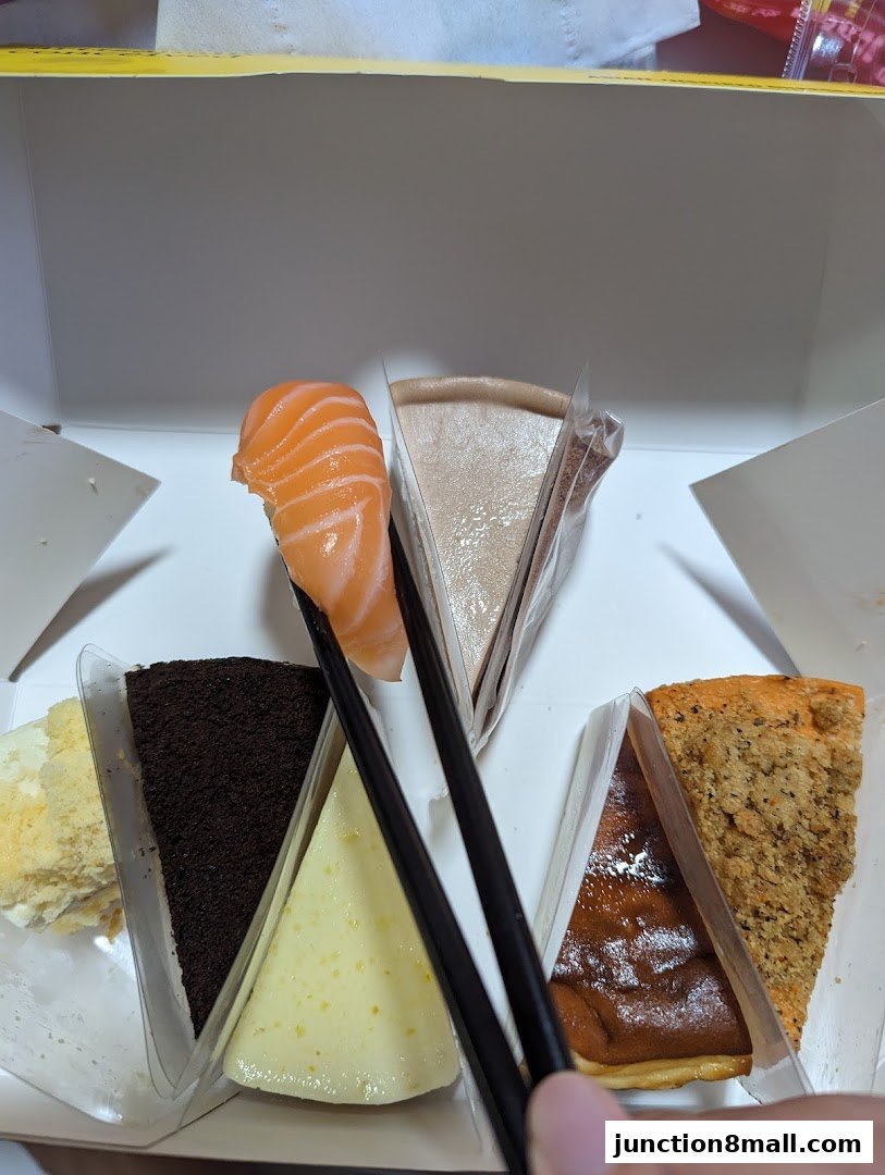 A box of assorted cake slices, with chopsticks holding a piece of salmon.