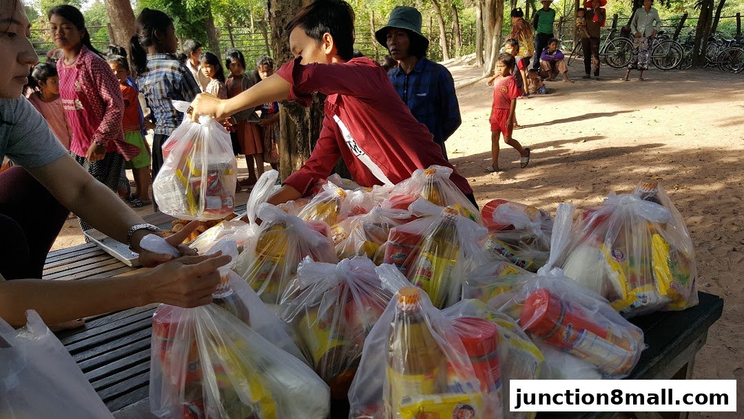 People distributing food packages to a crowd of children and adults outdoors.