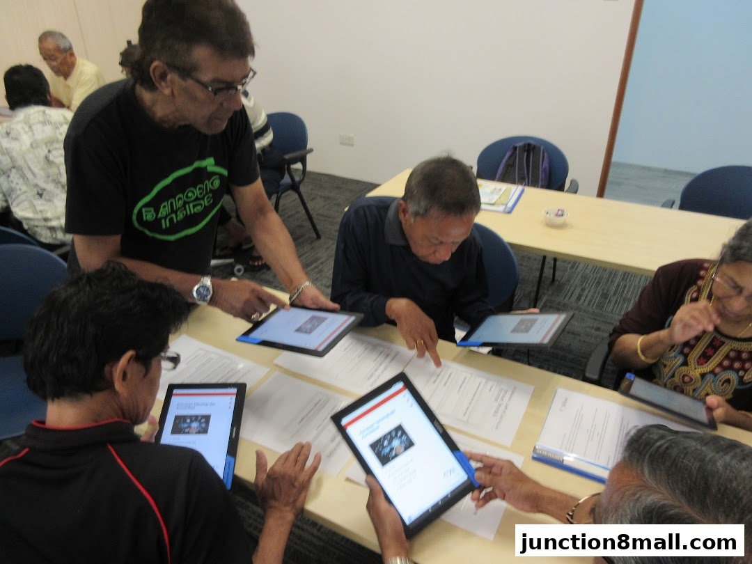 Seniors learning to use tablets in a classroom setting with instructor.